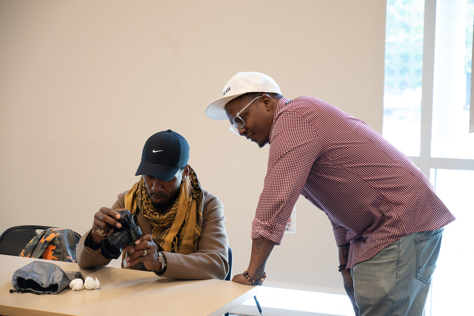 Two people working together over a digital camera at a workshop table