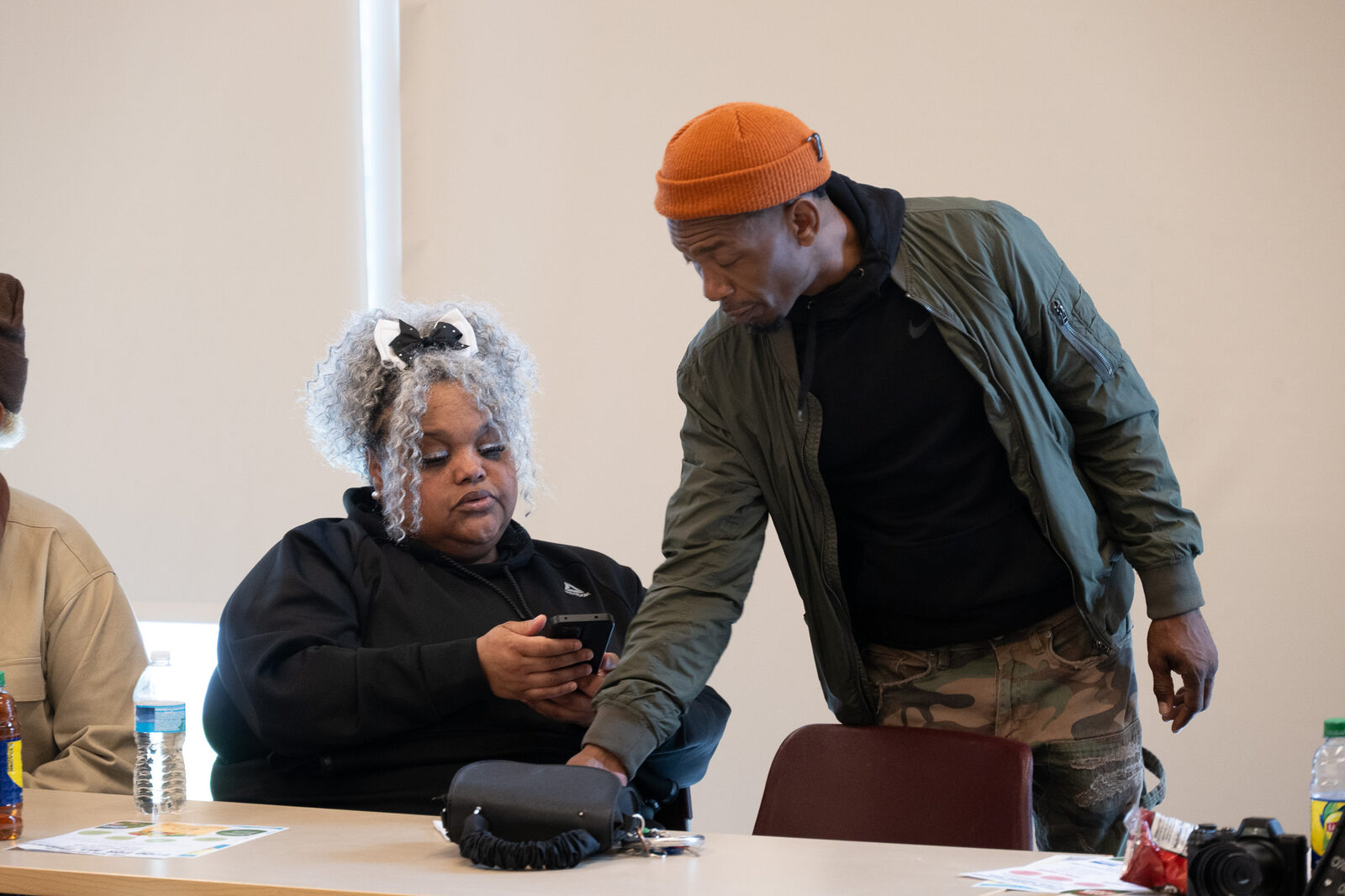 A teaching artist leans in to look at a woman's phone as she shares her work