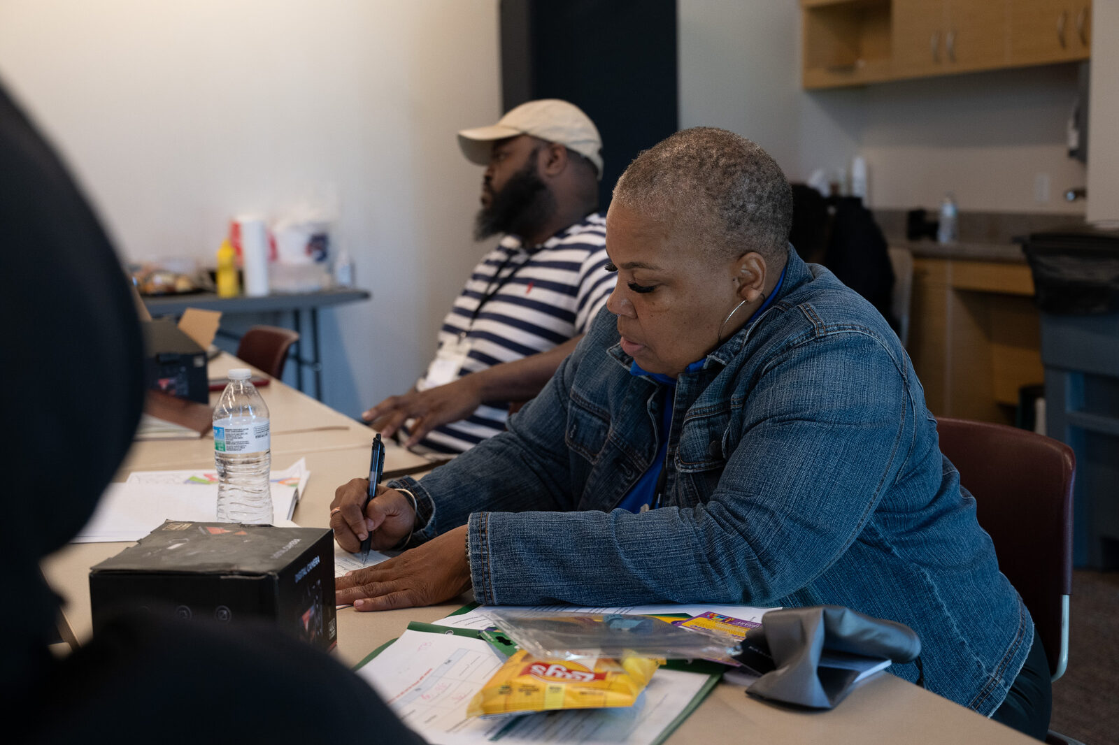 A woman writes notes at a workshop table
